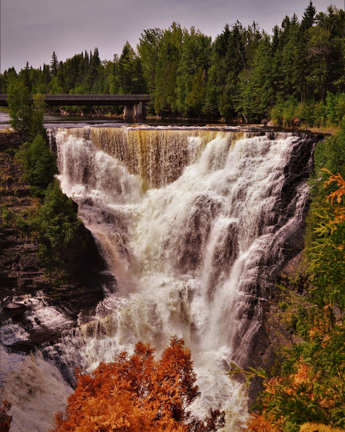 A wide waterfall in full flow beneath a bridge, near Thunder Bay, Ontario